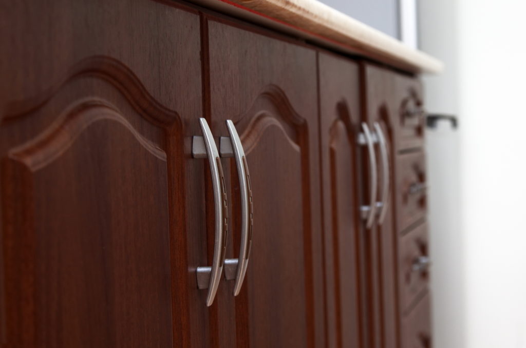 Close-up of brown wooden cabinets in home kitchen. 