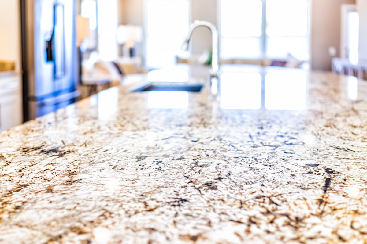 A close-up image of a granite countertop with a sink in the background in El Paso.
